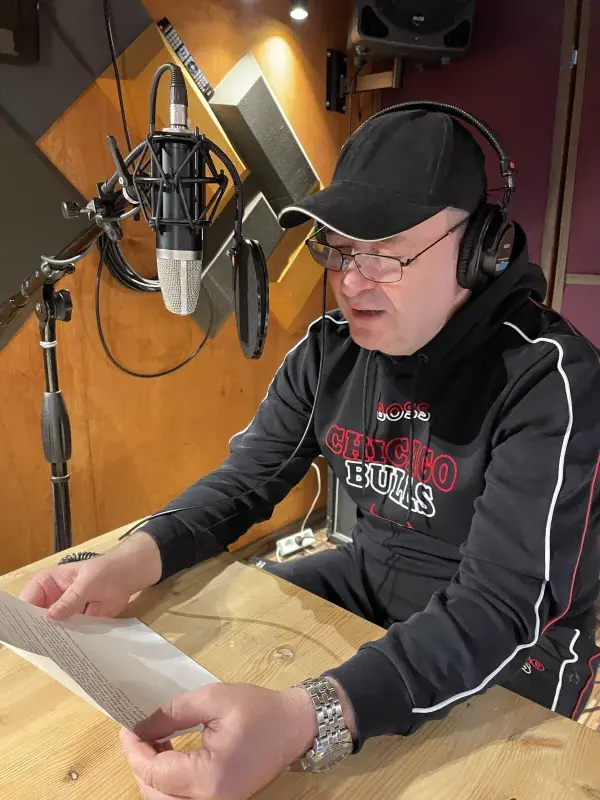 Jacek Rozenek czyta skrypt przy mikrofonie w studiu